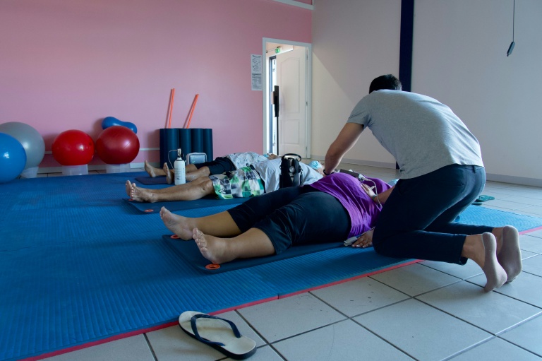 Un entraîneur aide des patients atteints d'obésité à faire des exercices de respiration au centre de santé spécialisé Ora Ora à Pirae, en Polynésie française, le 10 septembre 2021