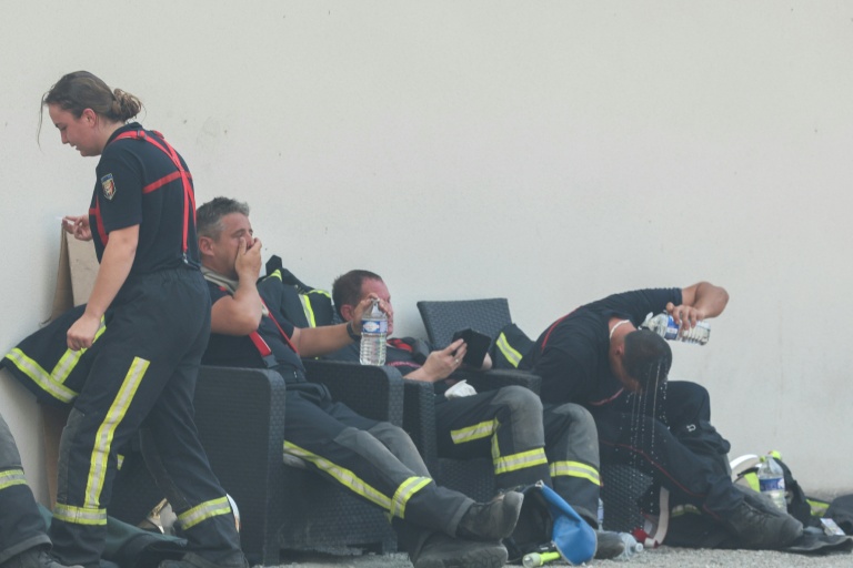 Des pompiers se reposent avec des bouteilles d'eau pendant une pause au cours des opérations de lutte contre un incendie de forêt près de Lanton, dans le sud-ouest de la France, le 29 juillet 2026
