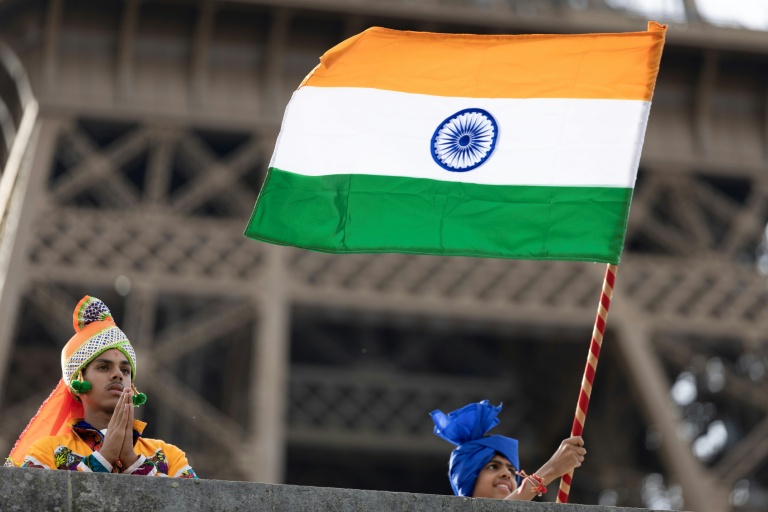 Des membres de la communauté hindoue Bochasanwasi Akshar Purushottam Swaminarayan Sanstha (BAPS) agitent des drapeaux indiens lors d'une cérémonie religieuse devant la tour Eiffel, avant un défilé fluvial sur la Seine à Paris, le 3 septembre 2026