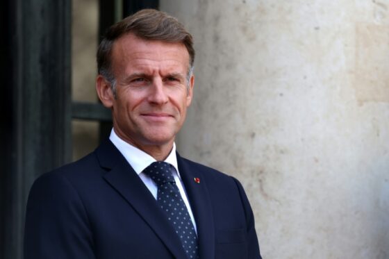 Emmanuel Macron souriant devant un bâtiment officiel