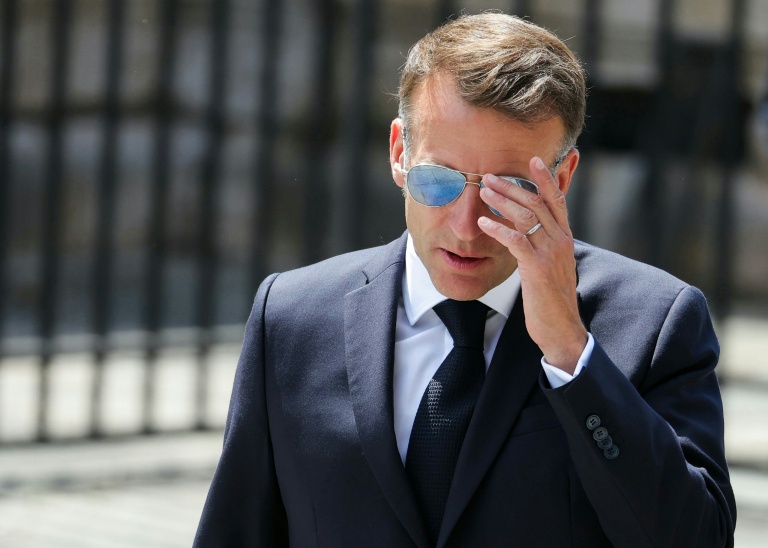 Emmanuel Macron portant des lunettes de soleil, se rendant à une réunion officielle.