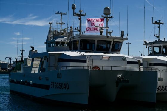 Bateau de pêche avec une banderole 'Pêcheurs en colère' sur le port.