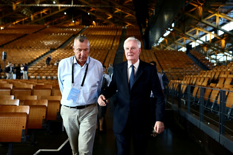 Le président de la fédération internationale de luge Einars Fogelis (G) échange avec Michel Barnier, l'ex Premier ministre et membre du comité exécutif des JO-2030, lors d'une inspection de la Halle Tony-Garnier à Lyon, le 14 septembre 2026