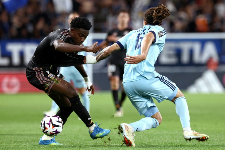 Un joueur du Paris FC en duel avec un joueur de l'Olympique Lyonnais lors d'un match.