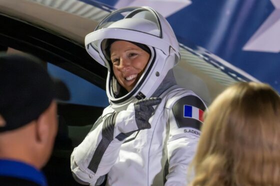 Sophie Adenot souriante dans sa combinaison spatiale avant une sortie dans l'espace.