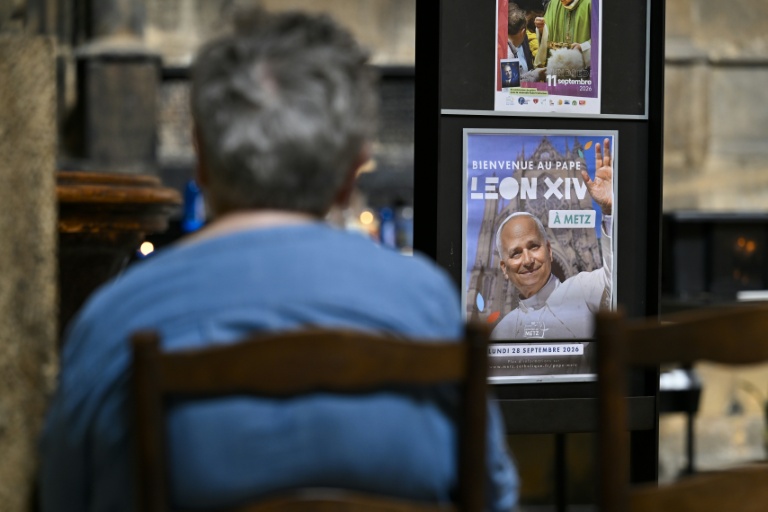 Une personne prie à côté d'une affiche annonçant la venue du pape Léon XIV dans la cathédrale Saint-Etienne de Metz le 3 septembre 2026