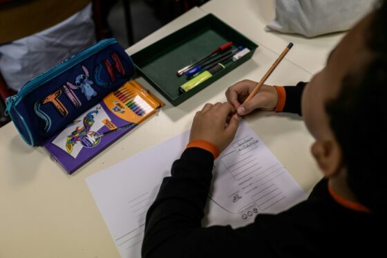 Un élève français écrit sur une feuille de papier pendant un cours.