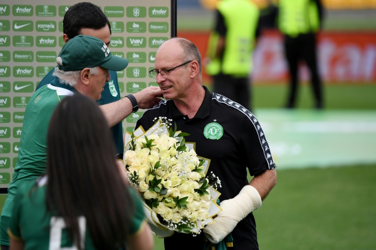 Le président du Chapecoense, Alex Passos (à droite), reçoit un bouquet de fleurs de la part des dirigeants de l'Atlético Nacional en hommage aux joueurs du Chapecoense décédés, avant un match amical entre les deux clubs à l'occasion du dixième anniversaire de l'accident, au stade Atanasio Girardot de Medellin, en Colombie, le 26 septembre 2026