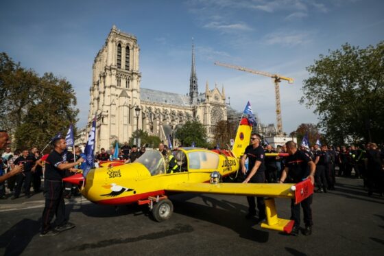 Des pompiers défilent à Paris avec un avion symbolique lors d'une manifestation.