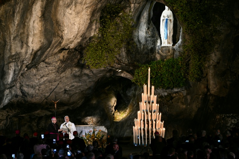 Le pape Léon XIV préside une prière avec des fidèles aux côtés de l'archevêque italien Diego Ravelli (à gauche) à la grotte de Massabielle, dans le sanctuaire de Notre-Dame de Lourdes, le 26 septembre 2026