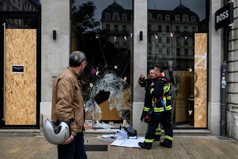 Des pompiers devant les vitrines brisées d’un commerce, au lendemain d'une manifestation contre la vie chère à Lyon, le 18 octobre 2026