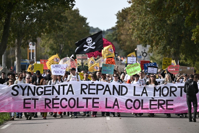 Manifestation contre Syngenta avec des pancartes et banderoles, exprimant la colère des manifestants sur l'utilisation des pesticides.