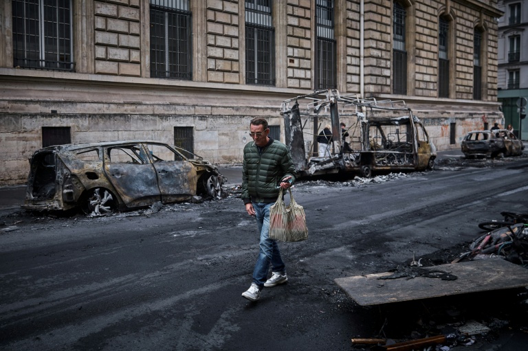 Un homme passe devant une rangée de véhicules calcinés, détruits lors d'une manifestation nationale contre la 