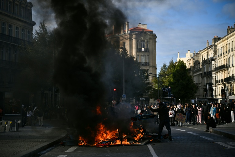 Un protestataire lance une trottinette électrique dans un feu lors d'une manifestation contre la vie chère à Bordeaux, le 17 octobre 2026