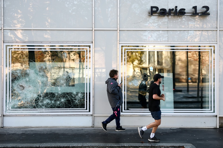 Des piétons passent devant l'enseigne d'un concessionnaire Audi dont les vitres ont été endommagées lors d'une manifestation, le 25 octobre 2026 à Paris