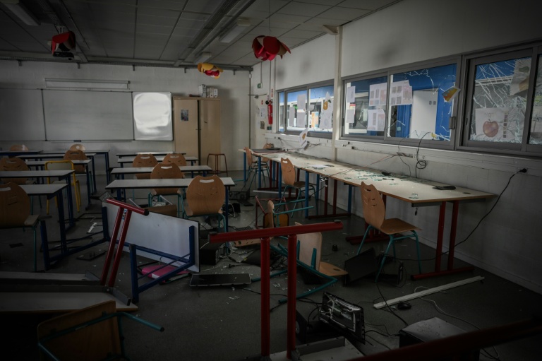 Des bureaux et des chaises renversés, des débris de verre et du matériel informatique endommagé dans une salle de classe du lycée 