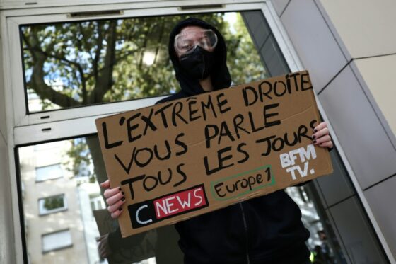 Manifestant avec une pancarte accusant les chaînes d'information de racisme.