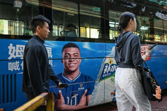 Kylian Mbappé sur une publicité en Chine, au milieu de passants.