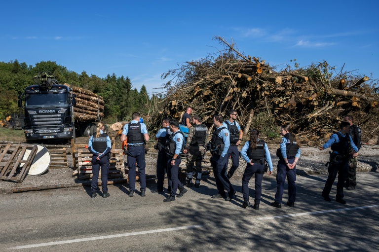 Des policiers le long d’une route, après que des manifestants ont bloqué un camion transportant des grumes dans le cadre de la construction controversée de l’autoroute A412, près de Perrignier, en Haute-Savoie, le 14 octobre 2026