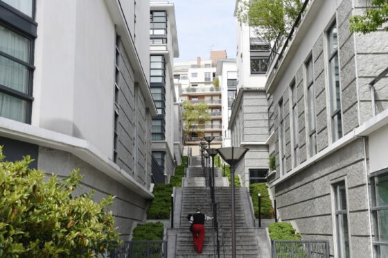 Un homme monte des escaliers dans un quartier résidentiel, illustrant le sujet de l'encadrement des loyers.