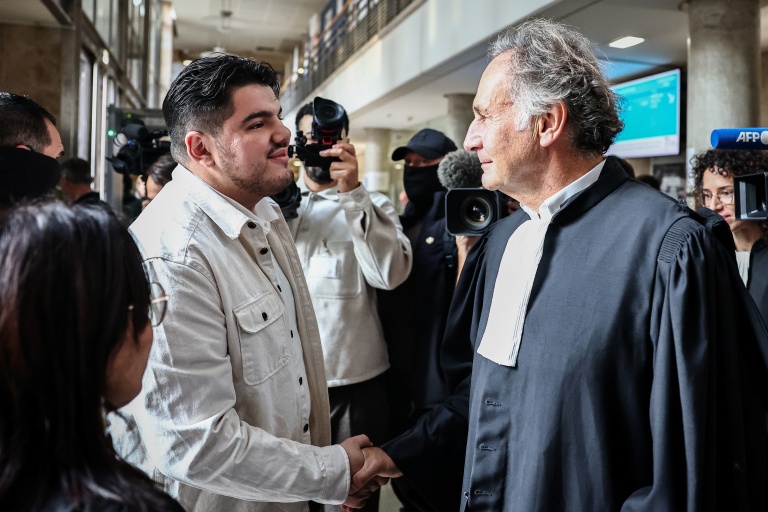 Amine Kessaci serre la main de son avocat, Me Pierre-Olivier Sur, au palais de justice d'Aix-en-Provence le 19 octobre 2026