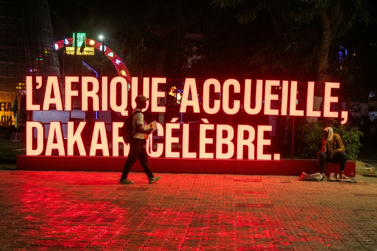 Des habitants passent, le 22 octobre 2026 à Dakar, devant l'un des panneaux des Jeux olympiques de la jeunesse 2026, qui se tiendront au Sénégal du 31 octobre au 13 novembre