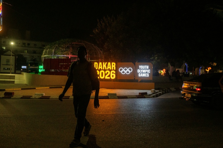Un homme passe, le 22 octobre 2026 à Dakar, devant un panneau des Jeux olympiques de la jeunesse (JOJ), qui se tiendront au Sénégal du 31 octobre au 13 novembre