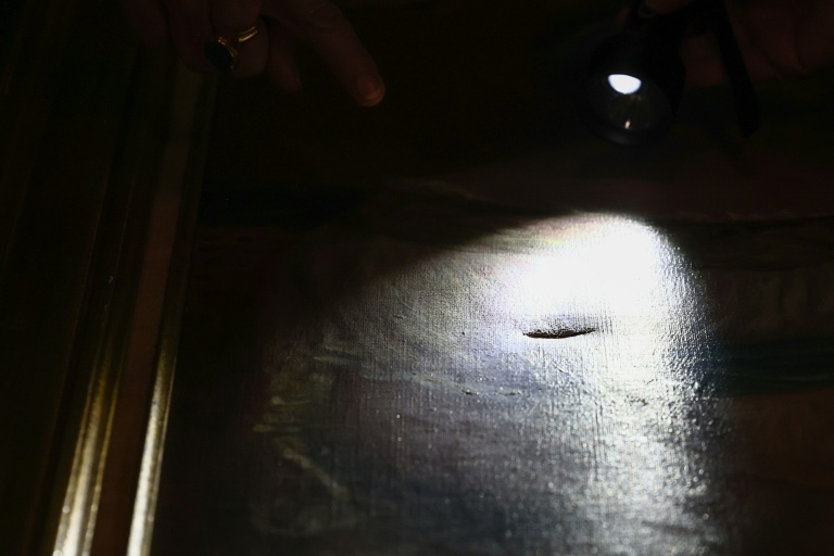 Une restauratrice montre une déchirure dans le tableau 